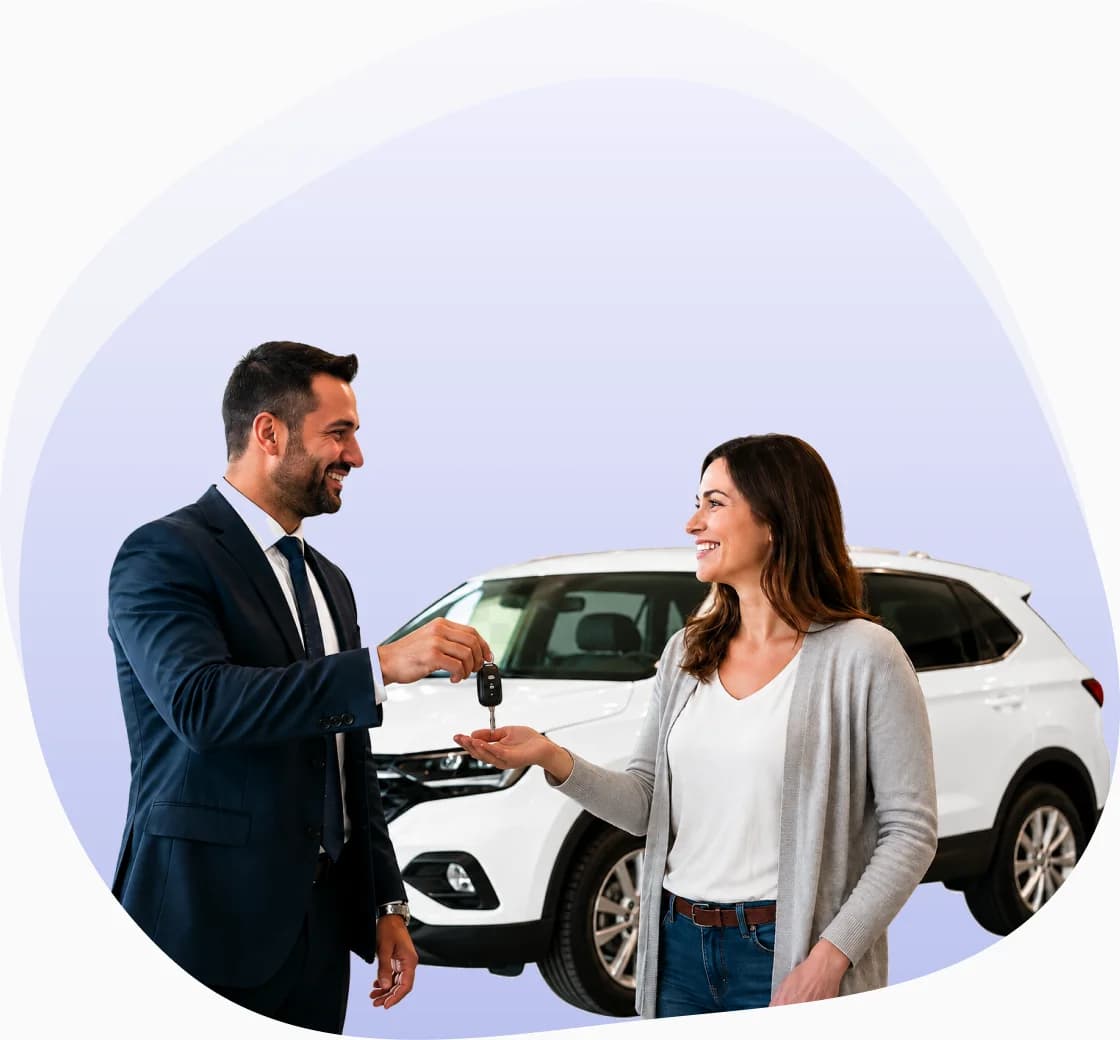 A salesperson handing car keys to a smiling customer